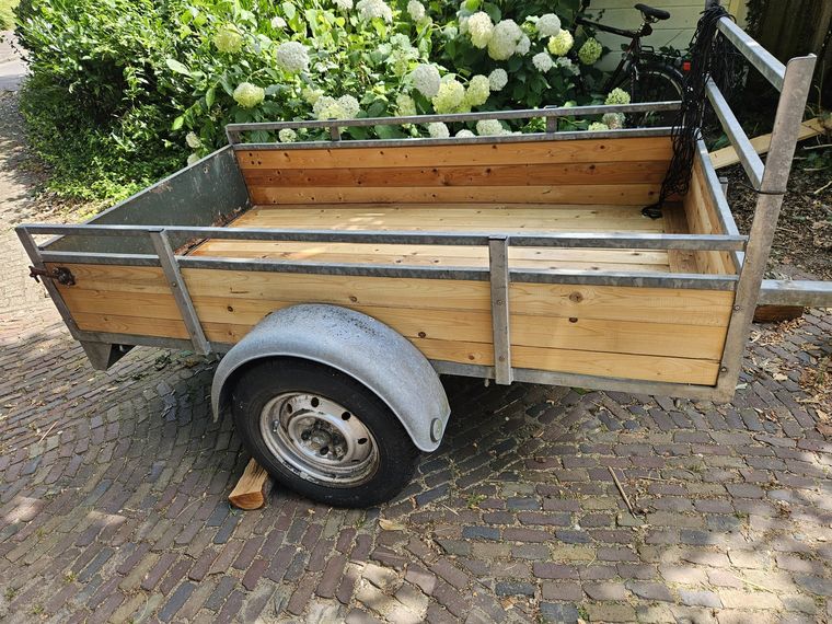 De ongeremde aanhangwagen van opzij: houten laadbak van 200 bij 115 centimeter op een verzinkt onderstel.
